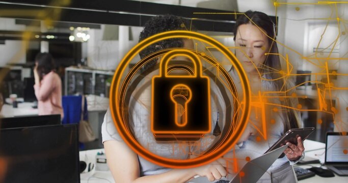 Working coworkers in business clothes pointing at laptop and tablet in office with orange lock icon