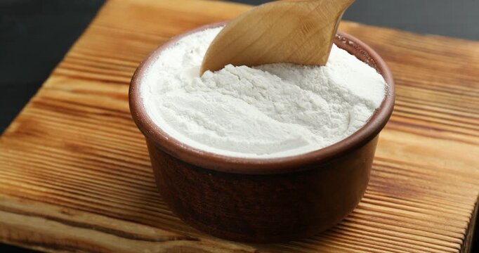 Woman taking baking powder with spoon at table, closeup