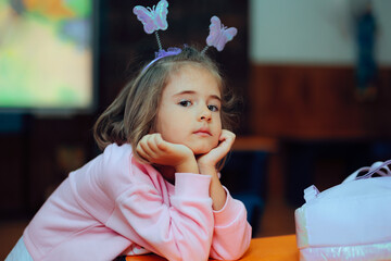 Little Girl with a Butterfly Headband Resting on a School Desk. Happy student thinking and waiting...