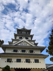 Naklejka premium Traditional Japanese castle tower under dramatic cloud sky in Imabari, Japan