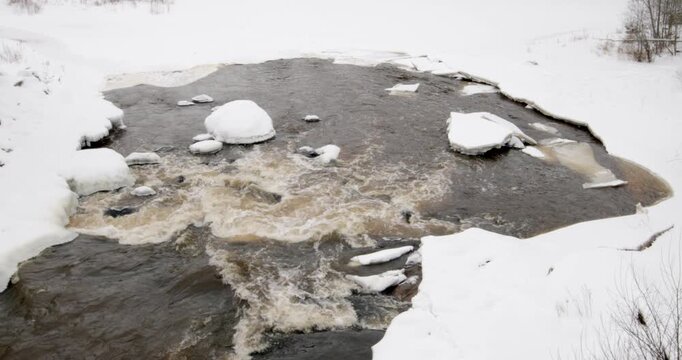 Water flows in a river that is partially frozenwith snow covered rocks in winter, Vantaankoski, Vantaa, Finland, Europe.