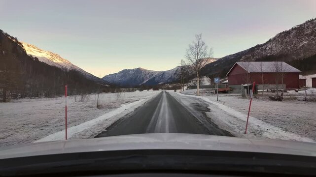 Dashboard camera view from a white car driving through the rural winter wonderland of Oeksendalen valley, near Kristiansund, Norway.