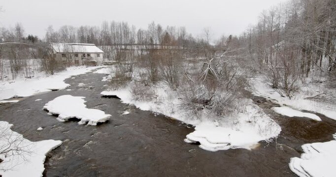 Vantaankoski rapids during the winter. The white building visible on the of the river is the Vantaankoski old mill in cloudy winter weather, Vantaa, Finland, Europe.