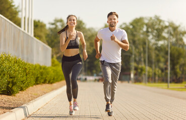 Fototapeta premium City road running and sport exercises of active couple, morning training and jogging of two happy strong runners. Young fit smiling woman and man running marathon. High motivation, workout concept