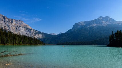 Obraz premium Morning Light Over Emerald Lake with Mountain Reflections 