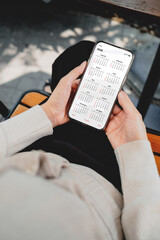 Woman checking calendar on smartphone outdoors. Digital planning, schedule management, time...