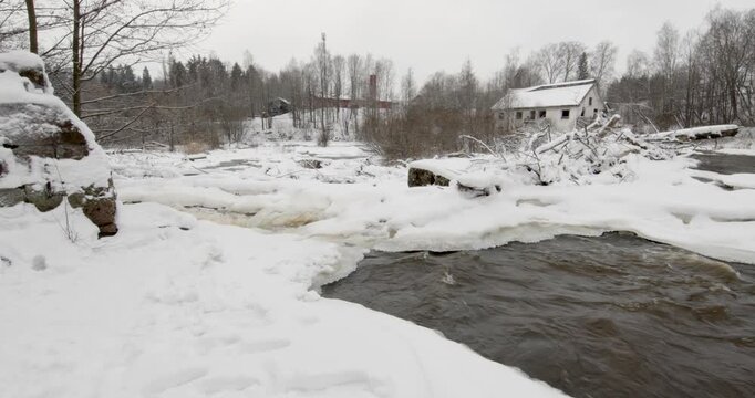 Vantaankoski rapids during the winter. The white building visible on the of the river is the Vantaankoski old mill in cloudy winter weather, Vantaa, Finland, Europe.