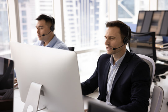 Videocall support. Multicultural business team two male virtual assistance consultants digital communication officers discuss customer questions using hands free audio devices looking at pc displays