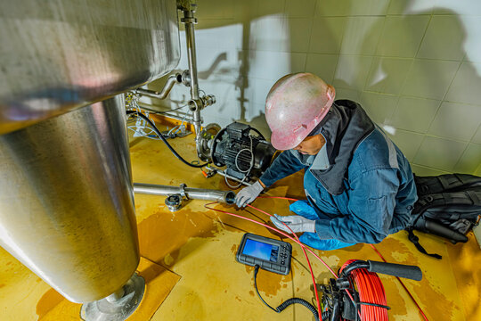 A man starts using a weld pipe stainless inspection camera. The light monitor shows images from the camera head