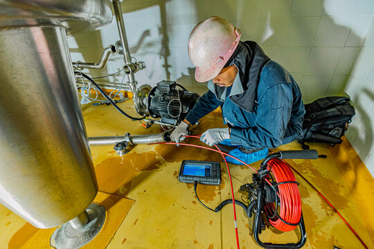 A man starts using a weld pipe stainless inspection camera. The light monitor shows images from the camera head