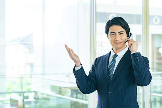 オフィスビルでヘッドセットをつけて案内する男性ビジネスパーソン