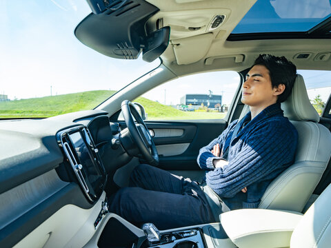 自動車の運転席で眠る男性ドライバー