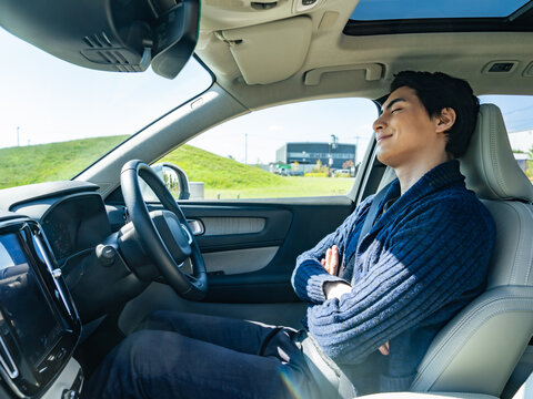 自動車の運転席で眠る男性ドライバー