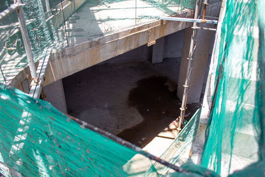 Jakarta, Indonesia - March 16, 2026: Opening hole in a concrete building construction floor surrounded by scaffolding and safety netting.