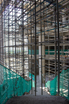 Jakarta, Indonesia - March 16, 2026: Building construction stairs surrounded by high iron scaffolding and green safety netting.