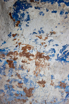 Texture of a concrete wall with remaining blue paint and iron rust stains due to oxidation on structural elements in a building construction area