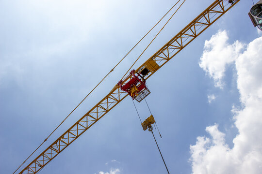 Jakarta, Indonesia - March 16, 2026: Trolley and hook block of a yellow tower crane operating at a high-rise construction site.