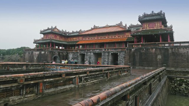 Tourists explore the Imperial City, a walled enclosure within the citadel of Hue, Vietnam. The structure showcases traditional Vietnamese architecture and history.