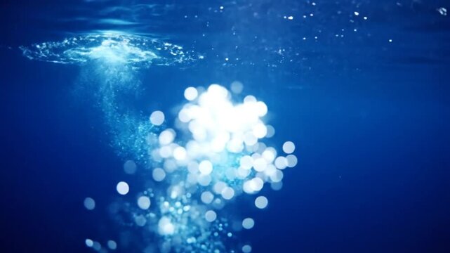 Underwater view of shimmering bubbles rising to the surface of a deep blue sea with sunlight