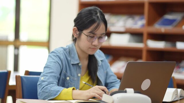 Focused student working on laptop in library study session educational environment intimate viewpoint concentration and learning