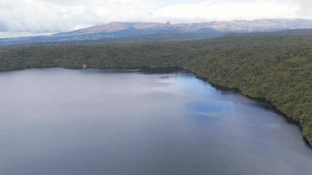 Stunning aerial perspective of Buey Lagoon surrounded by dense greenery and mountains under a cloudy sky.