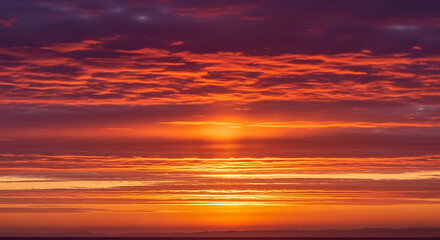 Fototapeta premium Vibrant orange sunset with scattered clouds