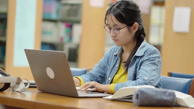Focused student typing on laptop in library study space concentration and learning environment