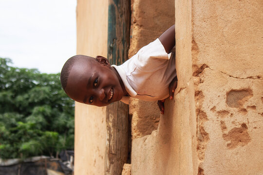A young African boy sits quietly beside a crumbling wall in a Namibian refugee camp. A powerful image capturing the reality of displacement, strength, and human dignity.