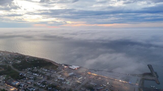 Aerial view of Matane city at dusk with river, fog, low clouds and city lights along St Lawrence River, Quebec, Canada. g.