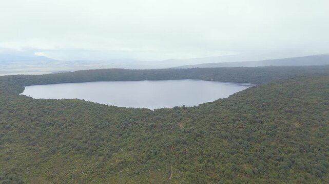 Overlooking Buey Lagoon surrounded by lush green vegetation under a cloudy sky. The landscape shows gradual proximity to the water.