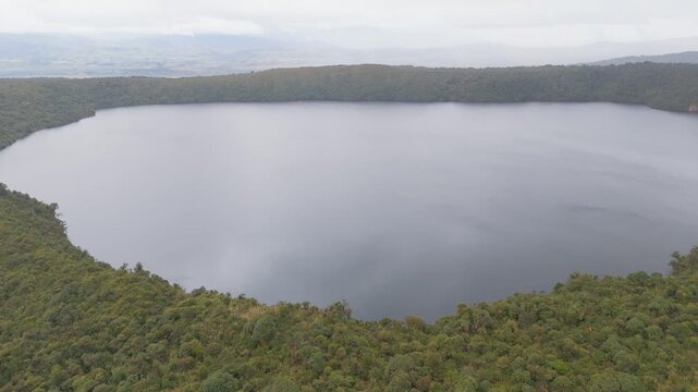 This serene view captures the expansive Buey Lagoon enveloped by verdant forests under overcast skies.