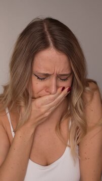 Young blonde woman feeling nauseous, covering her mouth and experiencing discomfort. Health problem, sickness and unwell condition concept