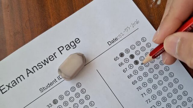 Hand marks answer on test sheet with pencil