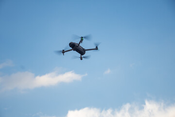 Fototapeta premium Modern Camera Drone Flying High in Blue Sky on Sunny Day
