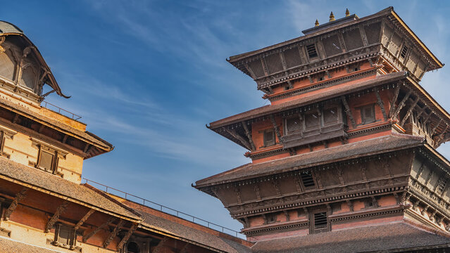 Ancient Newar architecture. A multi-tiered pagoda on a background of blue sky and clouds. Exquisite wood carvings. Decorative elements, sculptures, window grilles. Nepal. Kathmandu Durbar Square.