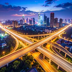 Fototapeta premium Aerial view of a cityscape at dusk with illuminated highway interchanges