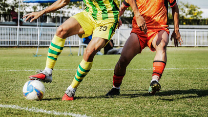 Close up sports action of football players competing for control of the ball on green field, highlighting powerful legs, athletic performance, outdoor competition © pixfly