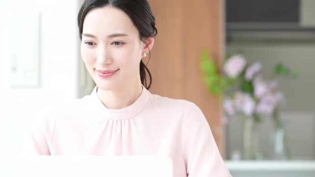 デスクで座るパソコンの仕事をするピンクの服を着た綺麗な女性の動画　キャリアウーマンなどの働く女性イメージ　最後にカメラ目線