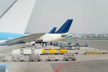 Airport apron scene with jet wing, cargo pallets and support vehicles, representing commercial...