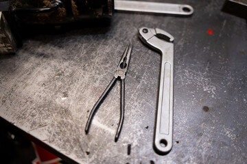 Pliers and service wrench on a worn metal bench surface, illustrating maintenance operations, hand tool use and repair station setup