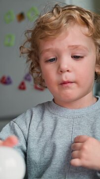 A young child interacts with a light bulb, demonstrating curiosity and focus.