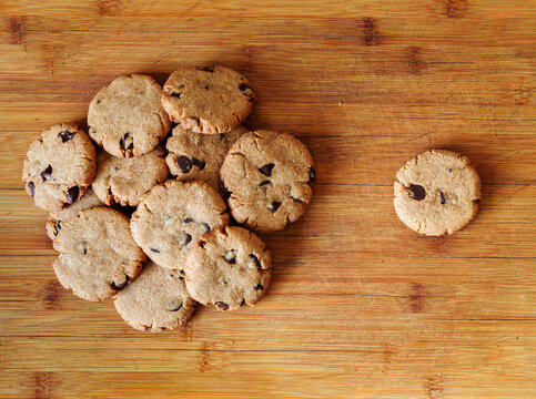 Homemade chocolate chip cookies pile next to single cookie