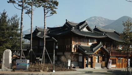 Obraz premium Traditional Korean hanok temple building with curved tile roof and mountain backdrop
