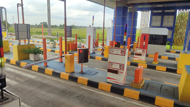 Jakarta, Indonesia - March 6, 2026: A modern toll booth with an automatic barrier system and payment machines on the highway in a cloudy daytime condition.