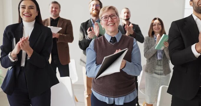 Audience applause at business seminar with speaker. Standing colleagues clapping in an office, recognizing team progress and celebrating training results. Clear theme of teamwork and success.