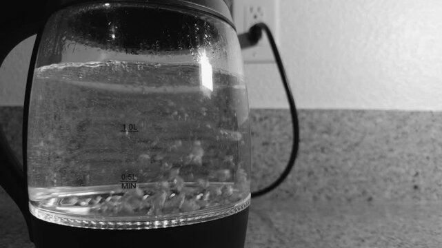 Black and white close up of water boiling in a glass electric kettle