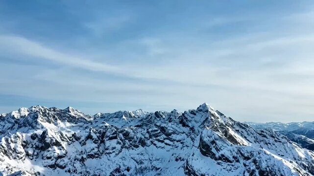 Majestic Snowy Peaks: A breathtaking panoramic view of towering mountain ranges blanketed in pristine snow, with a serene blue sky providing a contrasting backdrop.