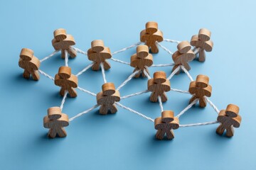 Obraz premium Network of Connection: Wooden figures interconnected by delicate threads illustrate the concept of community, emphasizing unity and the strength of interconnectedness.