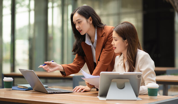 Two female coder or developer working overtime using a computer display in problem solving.