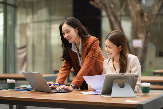Two female coder or developer working overtime using a computer display in problem solving.
